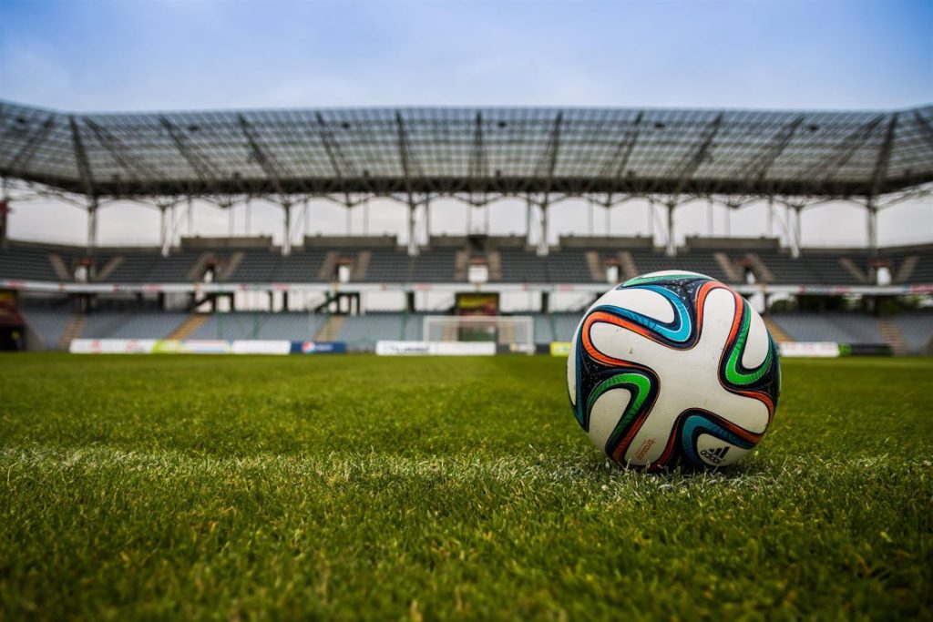 Voetbal op het gras voor een leeg stadion — illustratie van wedden op voetbal in Nederland