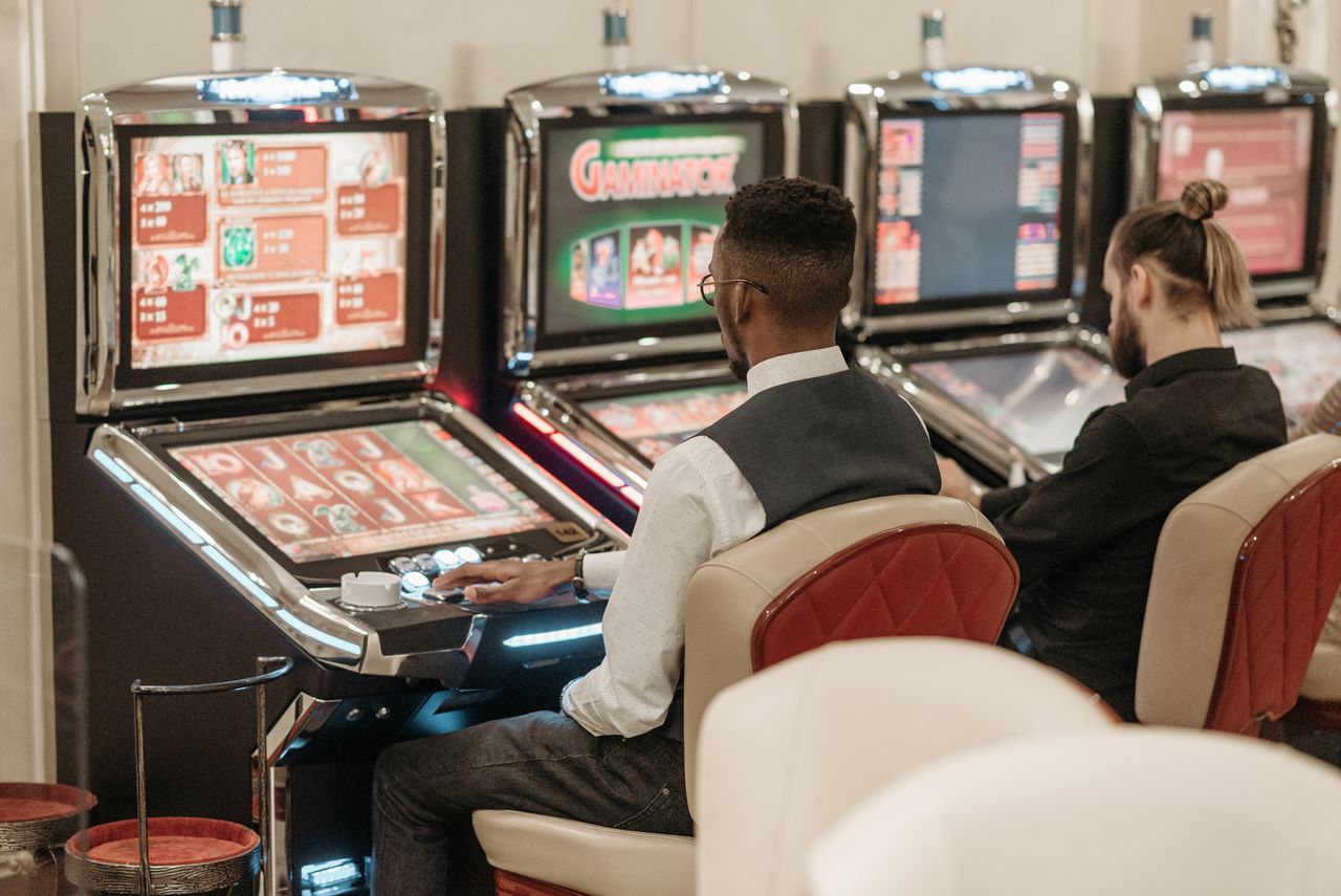 Twee spelers aan slot machines in casino – hoeveel spins krijg je voor 5 euro storting