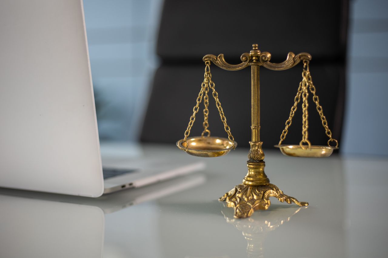 Gouden weegschaal van Vrouwe Justitia naast laptop – Wet op de kansspelen en casino zonder licentie